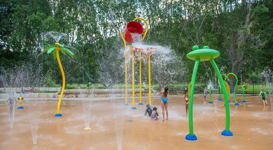Children playing under the water buckets and sprays of the splash park at Del Rio