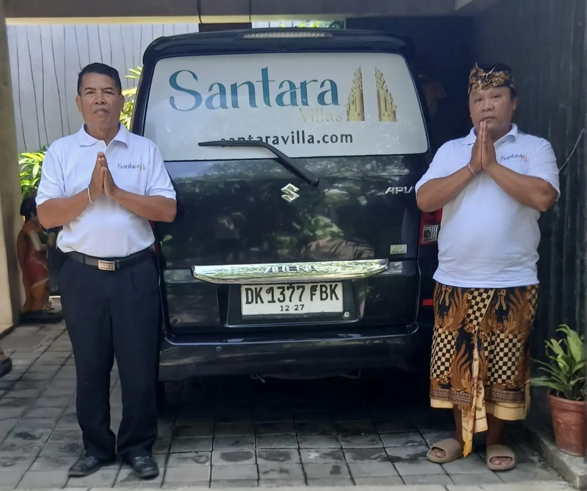 Two members of the Santara Villas team, hands pressed together in greeting, either side of the Santara-branded van